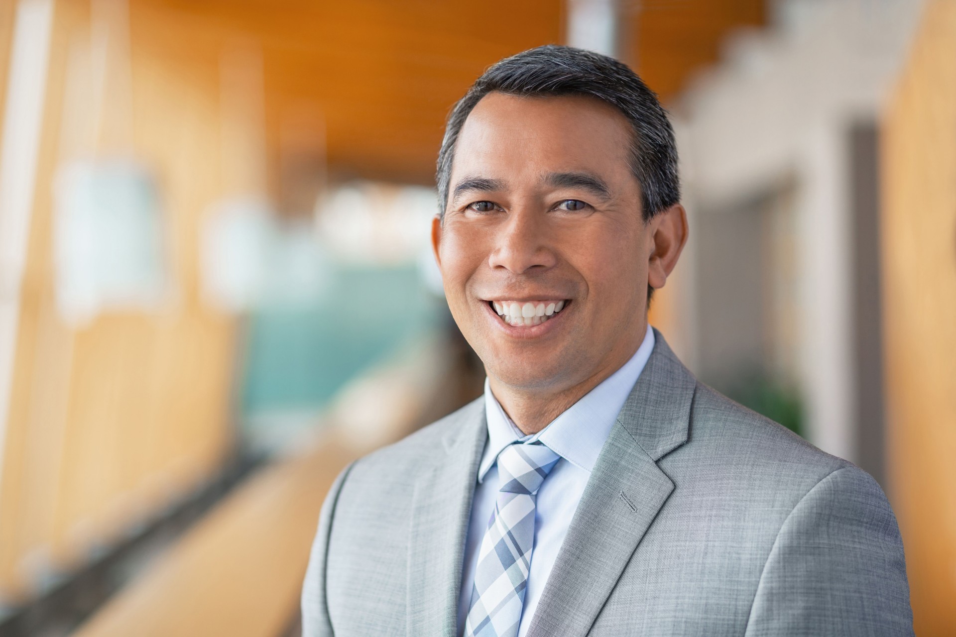 Portrait of mature multiracial Asian businessman in office lobby smiling